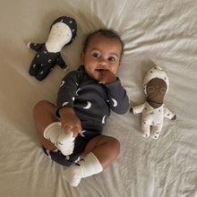 Baby smiling surrounded by Zoonie dolls