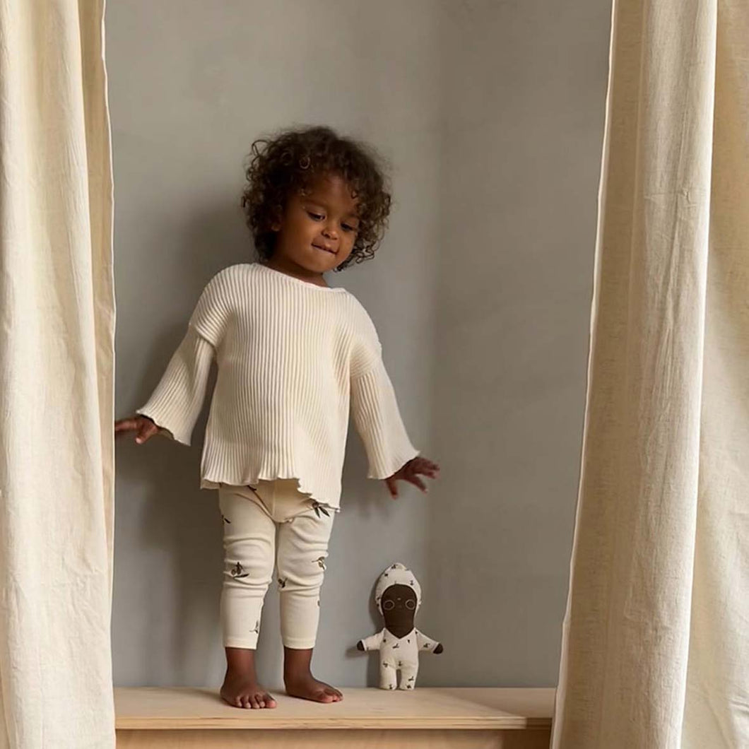 Toddler playing with Zoonie doll behind curtains